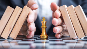 Businessman hand protect chess king figure
